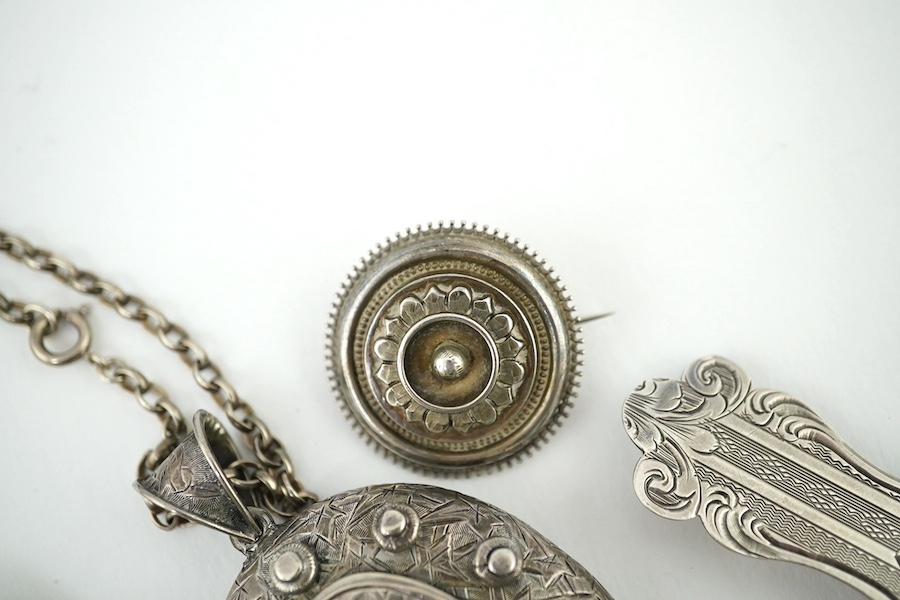 An oval engraved white metal enclosed locket and chain and five assorted white metal brooches. Condition - fair